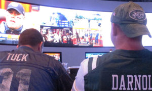 This Sept. 9, 2018 photo shows fans of the New York Giants and Jets watching a football game after placing bets in the sports betting lounge at the Ocean Casino Resort in Atlantic City, N.J. The coronavirus outbreak has added new wrinkles for bettors this year, but even so, the nation's sports books expect a record year of bets on football in 2020 from an antsy public that has been cooped up for months amid the pandemic. (AP Photo/Wayne Parry)