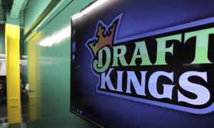 FILE - In this May 2, 2019, file photo, the DraftKings logo is displayed at the sports betting company headquarters in Boston. Sports gambling giant DraftKings won't give a former "Bachelor" contestant the $1 million prize for winning an online fantasy football contest after she and her husband were accused of cheating.Jade Roper-Tolbert beat more than 100,000 entries to take the top prize, but some in the fantasy sports community were quick to allege she coordinated with her husband, Tanner Tolbert, to submit more than the maximum 150 entries. Roper-Tolbert was no longer listed as the winner Saturday. A DraftKings statement says the company decided to update the standings for several contests and did not elaborate. (AP Photo/Charles Krupa, File)