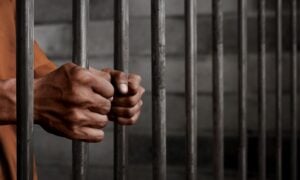 man stands behind jail bars