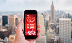 image of a person holding a phone with an online casino app, which experts say are inevitable for legalization in new york