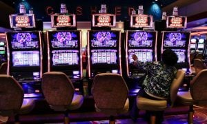 Woman plays slots at Resorts World Catskills for a story on January 2024 revenue generated by the four upstate casinos in New York