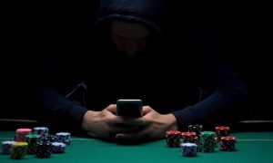 Image of a hooded figure gambling online for a story on New York losing $5 billion to illegal online casinos and sportsbooks in 2023.