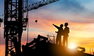 Workers in shadow overlooking a construction project