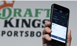 a hand holding a phone in front of a draftkings sportsbook logo